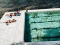 People sunbathing by a pool with clear water